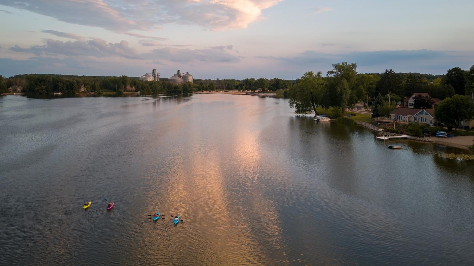 Random Lake, Wisconsin, from the air at sundown: kayakers on the water, shoreline homes on the right, the grain elevators on the far shore. Couillard Electric’s home base in Sheboygan County.